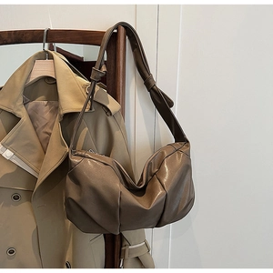 Detail of coffee brown pleated faux leather shoulder bag with natural soft texture