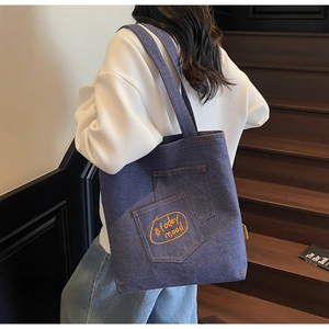 Detail of dark blue denim tote bag featuring yellow #today mood embroidery and front pockets