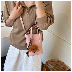 Detail view of pink crossbody phone bag with teddy dog charm on a female model