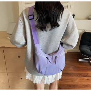 Détail du sac demi-lune en nylon violet avec deux zips frontaux et bandoulière tissée