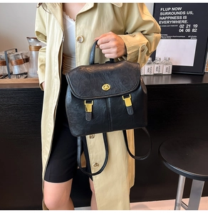 Close-up of black leather backpack featuring gold twist-lock and retro decorative buckles