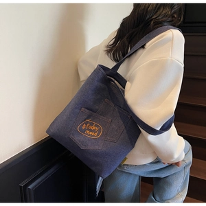 Detail of dark blue denim tote bag featuring an embroidered front pocket with today mood text