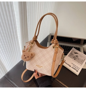 Dettaglio della borsa a secchiello a quadri beige con manici marroni e ciondolo orso