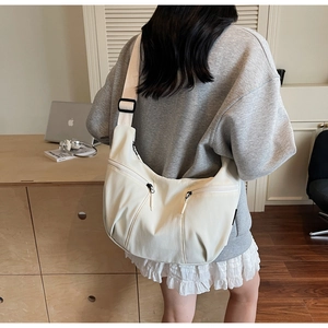 Vue détaillée du dos d'un mannequin portant un grand sac hobo en nylon de couleur crème