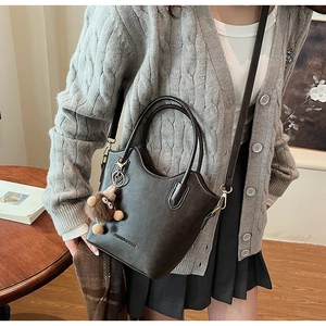 Detail of dark brown leather bucket bag featuring fashion text and cute plush monkey charm