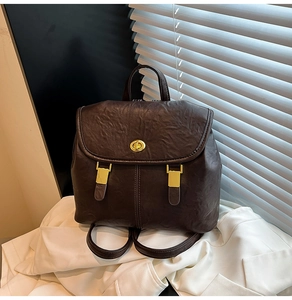 Detailed view of the dark brown wrinkled leather texture and golden twist lock on the backpack