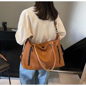 Brown faux leather travel tote bag with dual front zippers and round logo detail