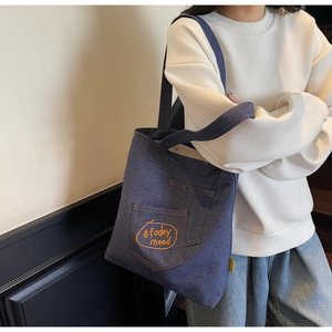 Close-up of dark blue denim tote bag with bright orange #today mood embroidery on pocket