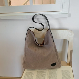 Detail of taupe suede tote bag with signature four-stitch patch and black leather strap