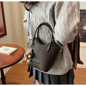 Detail of minimalist bucket bag with removable strap and cute plush monkey charm