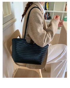 Détail d'un grand sac cabas noir en cuir tressé porté à l'épaule pour un look chic