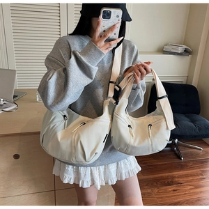Detail of off-white crescent crossbody bag set showing waterproof nylon texture and zippers