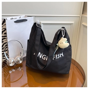 Detail of black large tote bag with Angel Fish logo and cute yellow plush keychain
