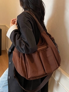 Deep brown large capacity nylon shoulder bag with multi-pocket design shown on a model