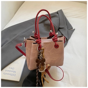 Detail of pink bucket bag with red handles, bow charm, and inner zipper pocket
