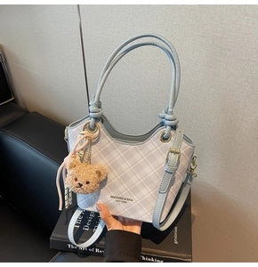 Dettaglio borsa a quadri celeste con ciondolo orsetto di peluche e tracolla regolabile