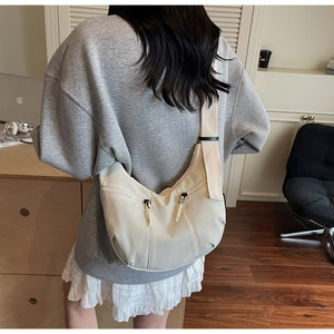 Gros plan détaillé d'un sac bandoulière beige en forme de croissant avec large sangle