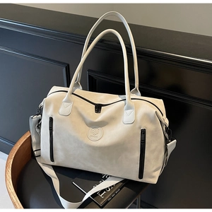 Close-up of beige travel bag with NJ logo, adjustable strap and side zipper pockets