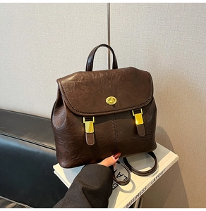 Detail of dark brown leather backpack featuring golden turn-lock clasp and flap closure