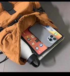 Primer plano del interior de la mochila naranja que muestra espacio para tablet y móvil