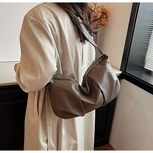 Model wearing dark khaki underarm bag with soft pleated texture and wide strap detail