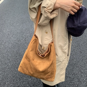 Brown suede hobo shoulder bag styled with a beige trench coat for an autumn look