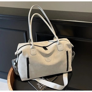 Detail of a large cream travel tote with dual handles and NING JIA logo on dark seat