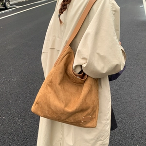 Outdoor lifestyle view of large brown suede tote bag worn with beige trench coat