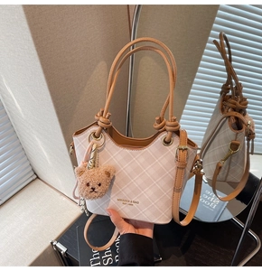 Dettaglio della borsa a quadri beige con ciondolo a orsetto e doppia tracolla