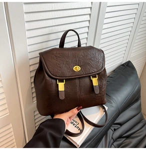 Close-up of vintage brown leather backpack featuring a gold buckle and twist-lock closure