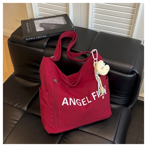 Close-up of red canvas tote bag with side zipper and white plush cloud charm accessory