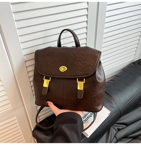 Detail of dark brown leather backpack with golden twist lock and metallic accents
