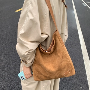 Close-up of brown matte suede tote bag featuring iconic white four-corner stitching