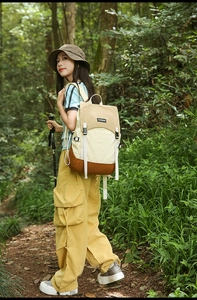 Outdoor color-block backpack with flap and buckle closure shown in a forest setting