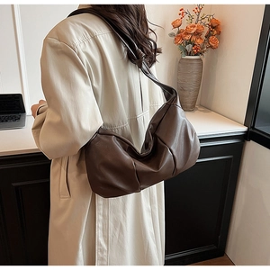 Detail of soft brown leather shoulder bag with wide strap and unique knot design