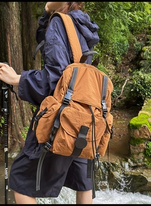 Mochila de nailon marrón para exteriores con cordón y hebillas funcionales en el bosque