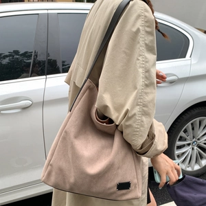 Detailed view of oatmeal suede tote bag with signature white four-corner stitching accent