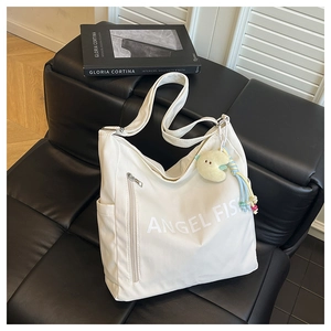 Close-up of white nylon tote bag with Angel Fish logo and yellow moon plush charm