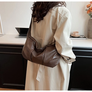 Detail view of slouchy brown leather shoulder bag with textured pleats and wide strap