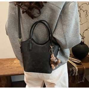 Black vintage leather bucket bag with brown plush pendant shown on a model
