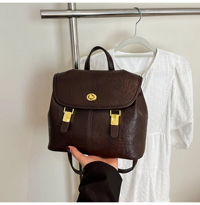 Close-up of a deep brown vintage backpack featuring a golden metallic twist lock closure