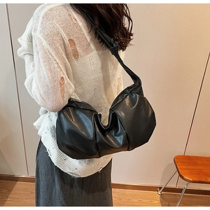 Side view of black leather pleated underarm bag showing texture and shoulder drape