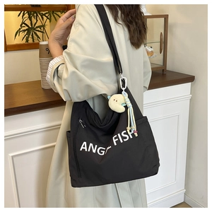 Detail of black canvas tote bag with white lettering and yellow moon plush charm