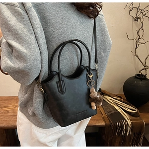 Detail of black wave-shaped bucket bag with plush bear charm and fashion logo