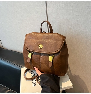 Detailed close-up of dark brown leather backpack with golden twist lock and vintage hardware