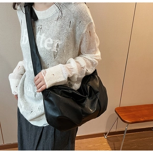 Detailed view of black pleated faux leather hobo bag with wide shoulder strap