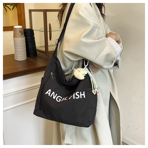 Close-up of black canvas tote bag with Angelfish logo and cute plush charm detail