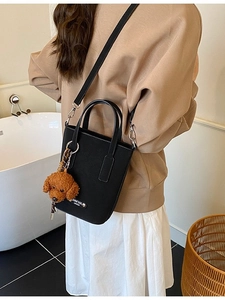 Chic black faux leather crossbody bag for women with a cute brown teddy bear charm accessory
