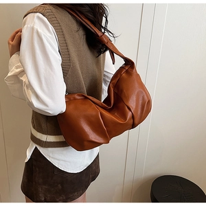 Detailed side view of brown pleated shoulder bag showing soft faux leather texture