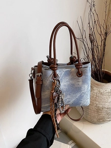 Retro light blue denim bucket bag with brown leather handles and butterfly bow accent